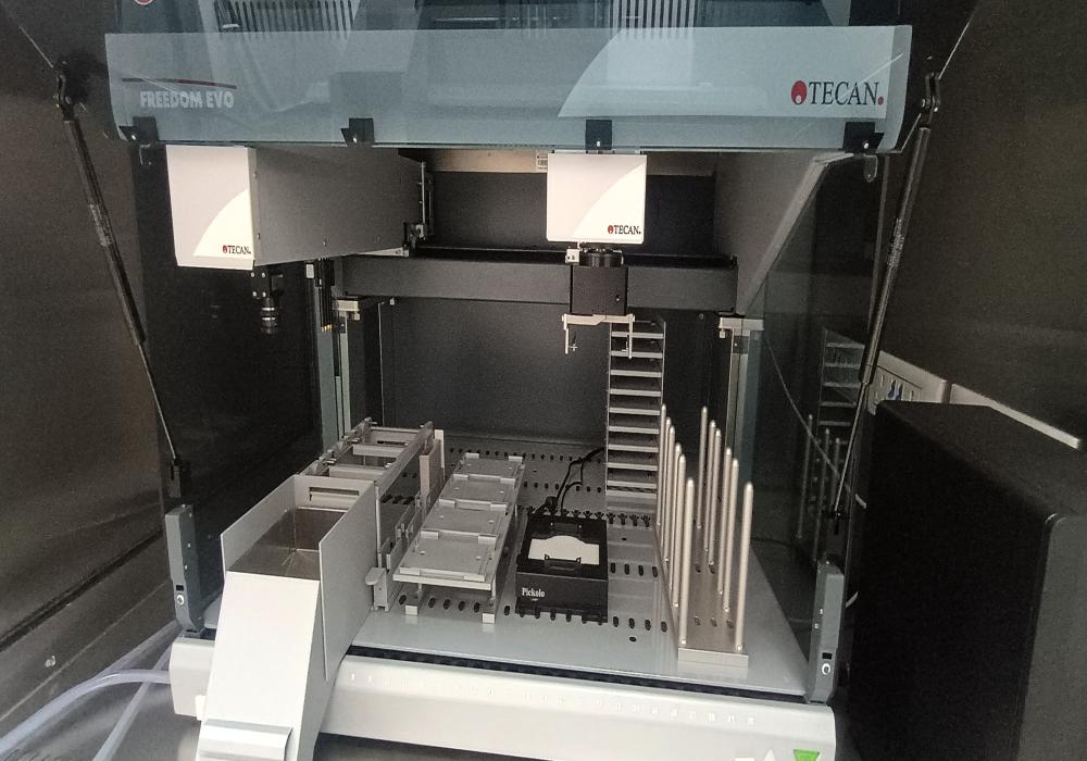 Freedom EVO100- Robotic colony picker station with 4-liquid handling channels; RoMA (robotic arm) on the top-right side, CCD camera and stage at the bottom attached to the stage; plate stackers on extreme right; and tip box stacking at extreme towards left side. 
